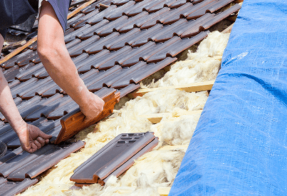 Roofer performing repair work on damaged roof tiles