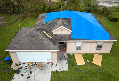 House with storm-damaged roof covered by emergency blue tarp
